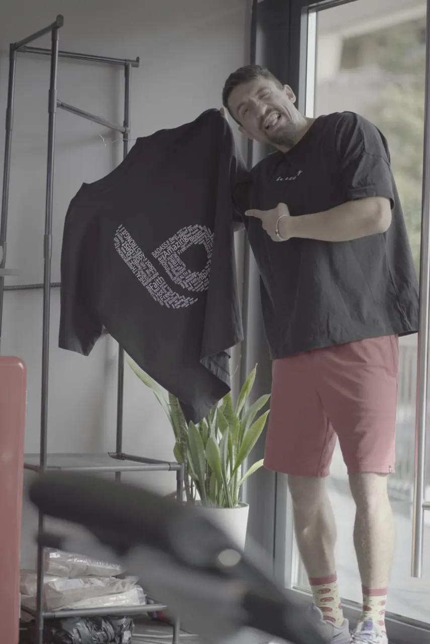 Maris Bogdan zâmbind în studio, cu un tricou Be Strong Studio în mână